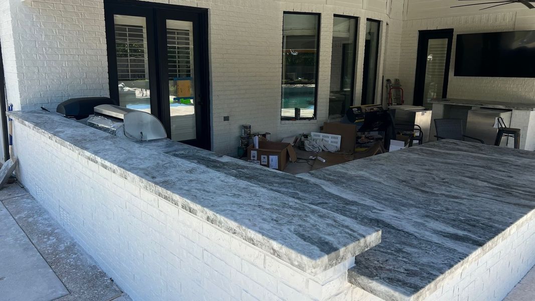 Outdoor patio with white stucco walls, gray concrete floor, and glass doors leading inside