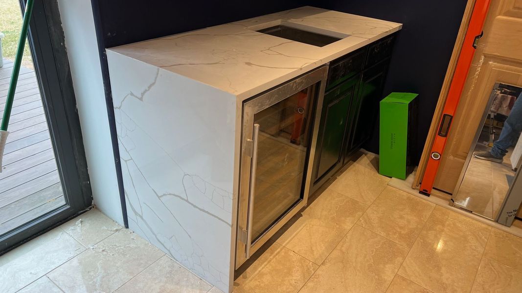 White utility cabinet with a glass door beside a sliding glass door in a tiled room, with a green bin nearby.