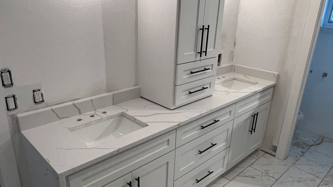 White bathroom vanity with sink, drawers, and a built-in water heater beside a tiled shower area