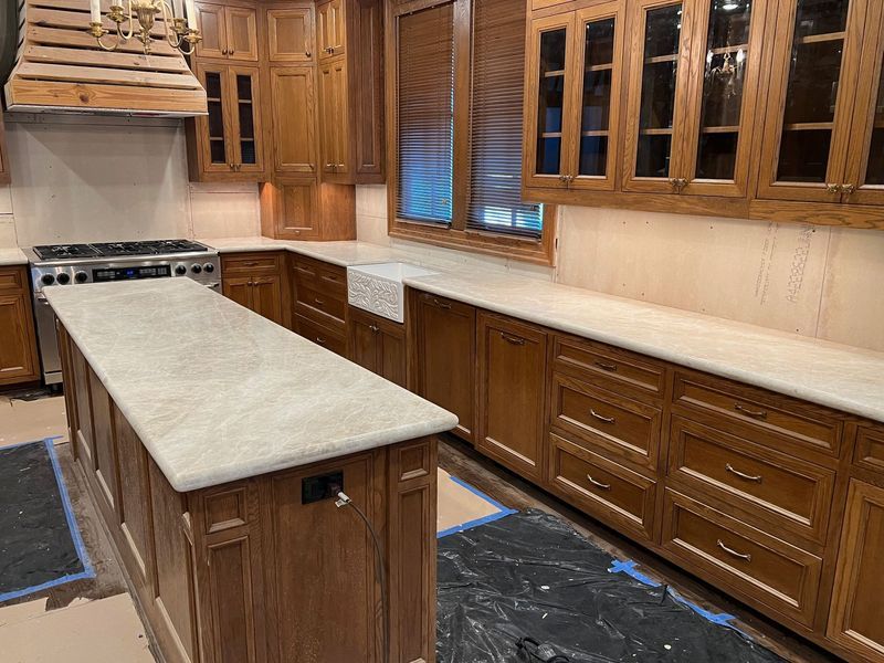 Quartzite Countertops Wooden kitchen with long island, light countertops, and built-in cabinets along the wall.