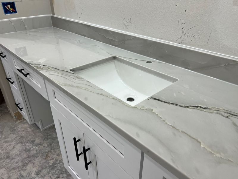 White bathroom vanity with double sink and marble countertop, showing a long crack across the surface