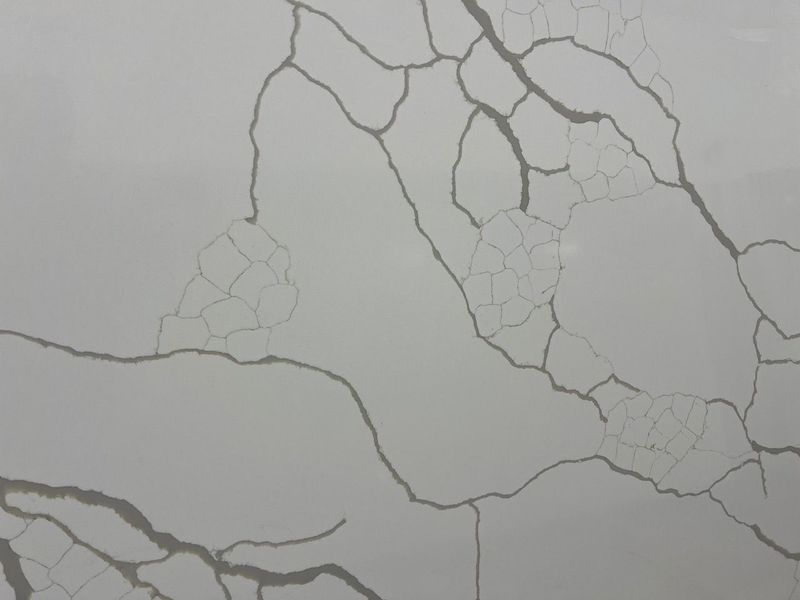 Cracked light gray wall with branching fissures across the surface