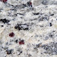 Close-up of white and gray speckled granite with small dark red mineral flecks