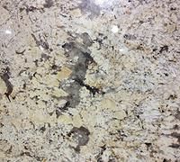 Close-up of light gray and tan granite with dark mineral specks and a rough central patch