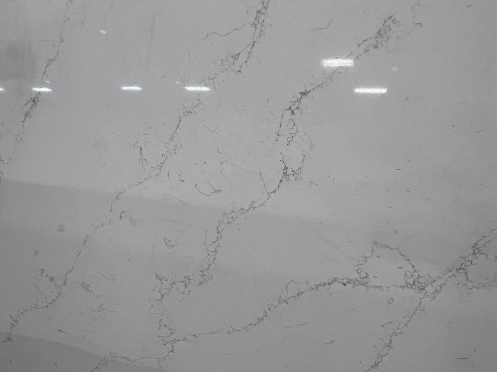 Light gray marble surface with thin dark veining and subtle white reflections