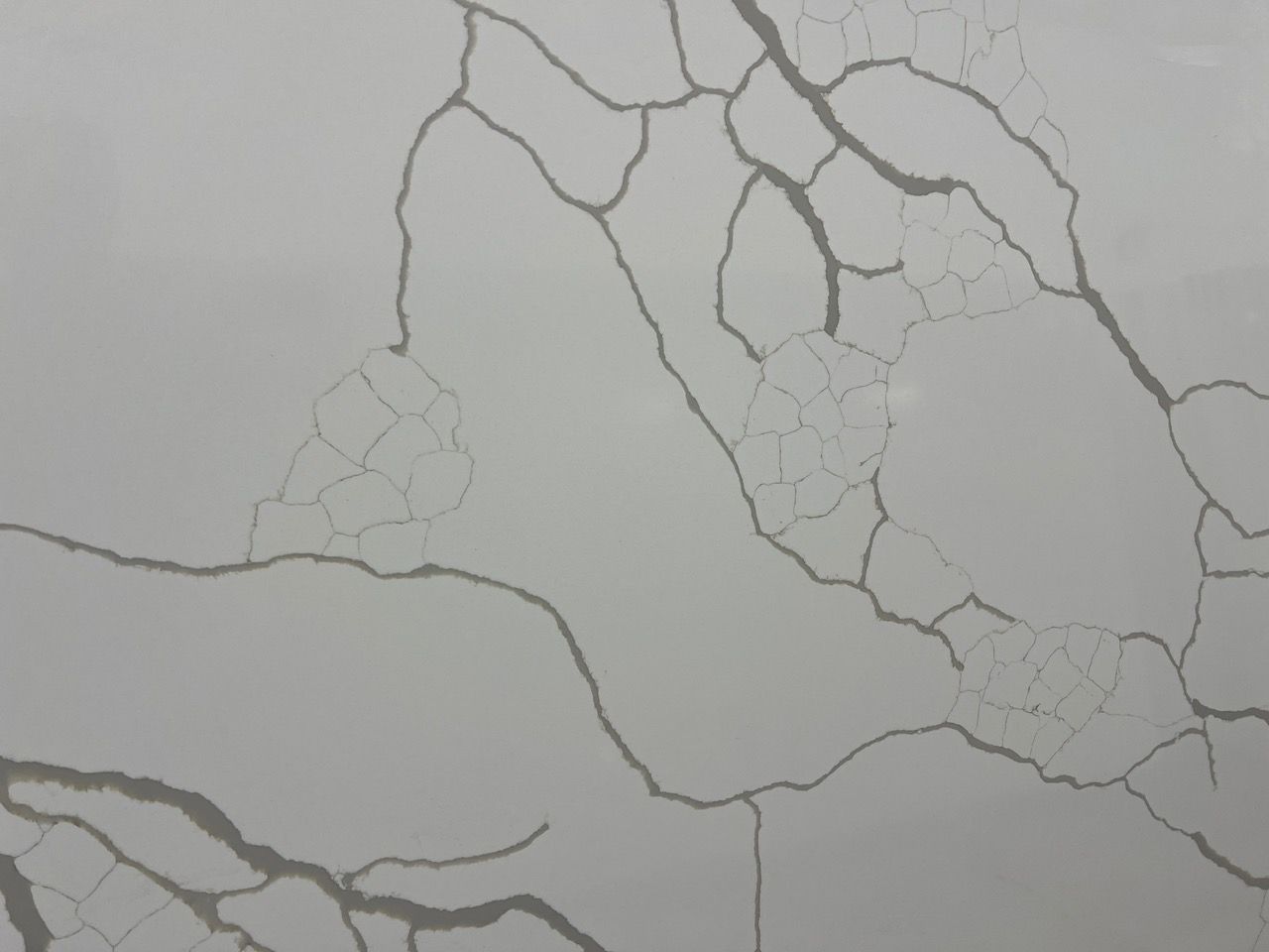 Close-up of a cracked gray wall with thin branching fissures