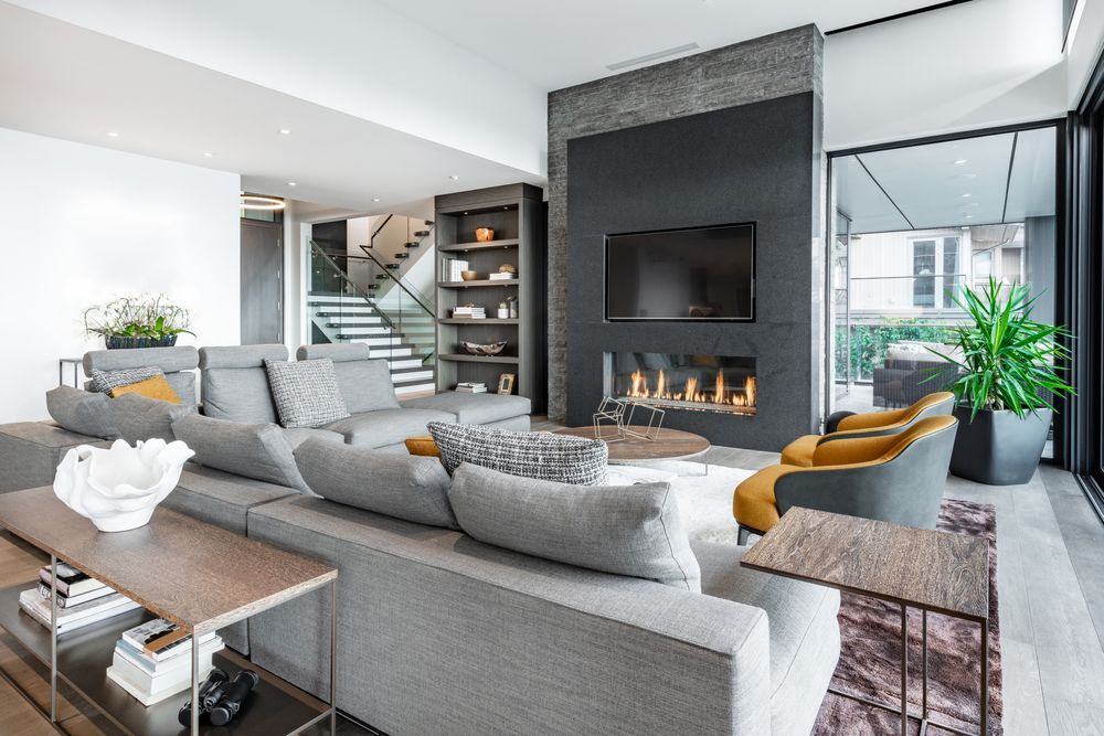 Modern living room with gray sectional sofa, fireplace, and large windows