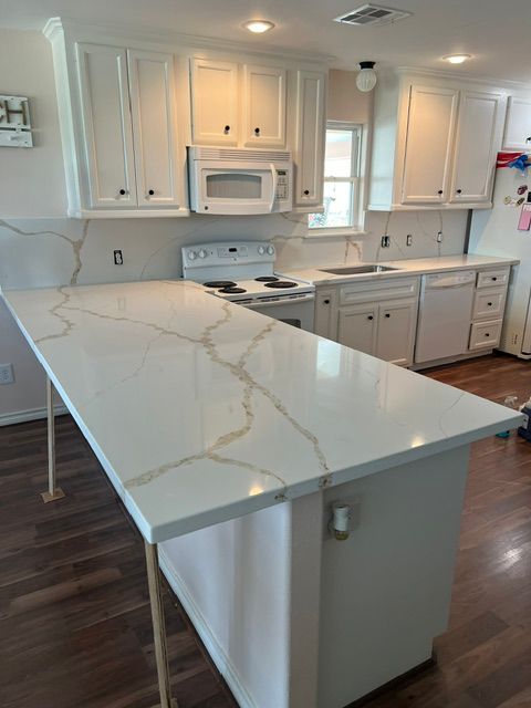Modern white kitchen with marble island, gray cabinets, white appliances, and wood floors
