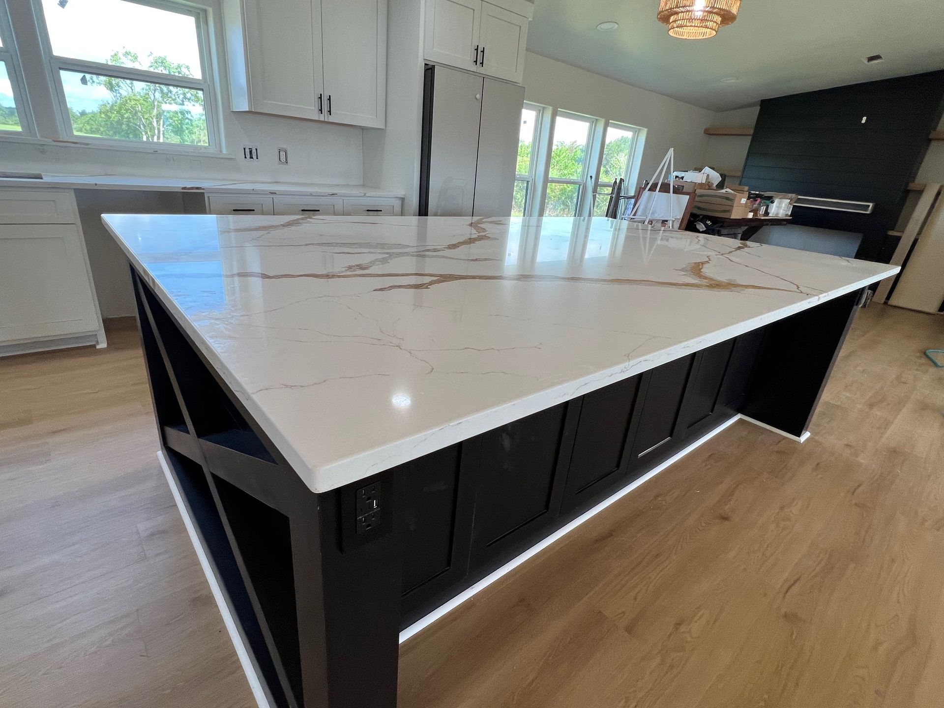 Modern kitchen island with white marble countertop and dark cabinets in a bright open kitchen