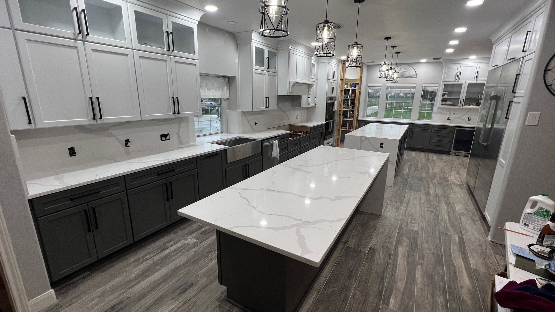 Modern kitchen showroom with white cabinets, dark lower cabinets, and a large central island with marble-look countertop