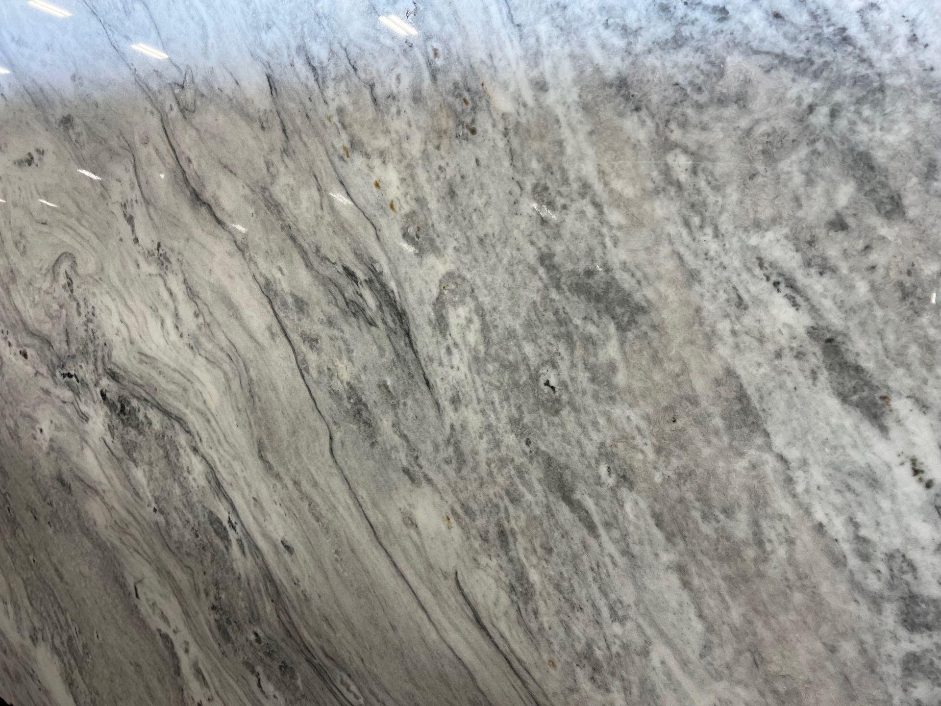 Close-up of a gray and white marbled stone surface with dark veins and a rough texture