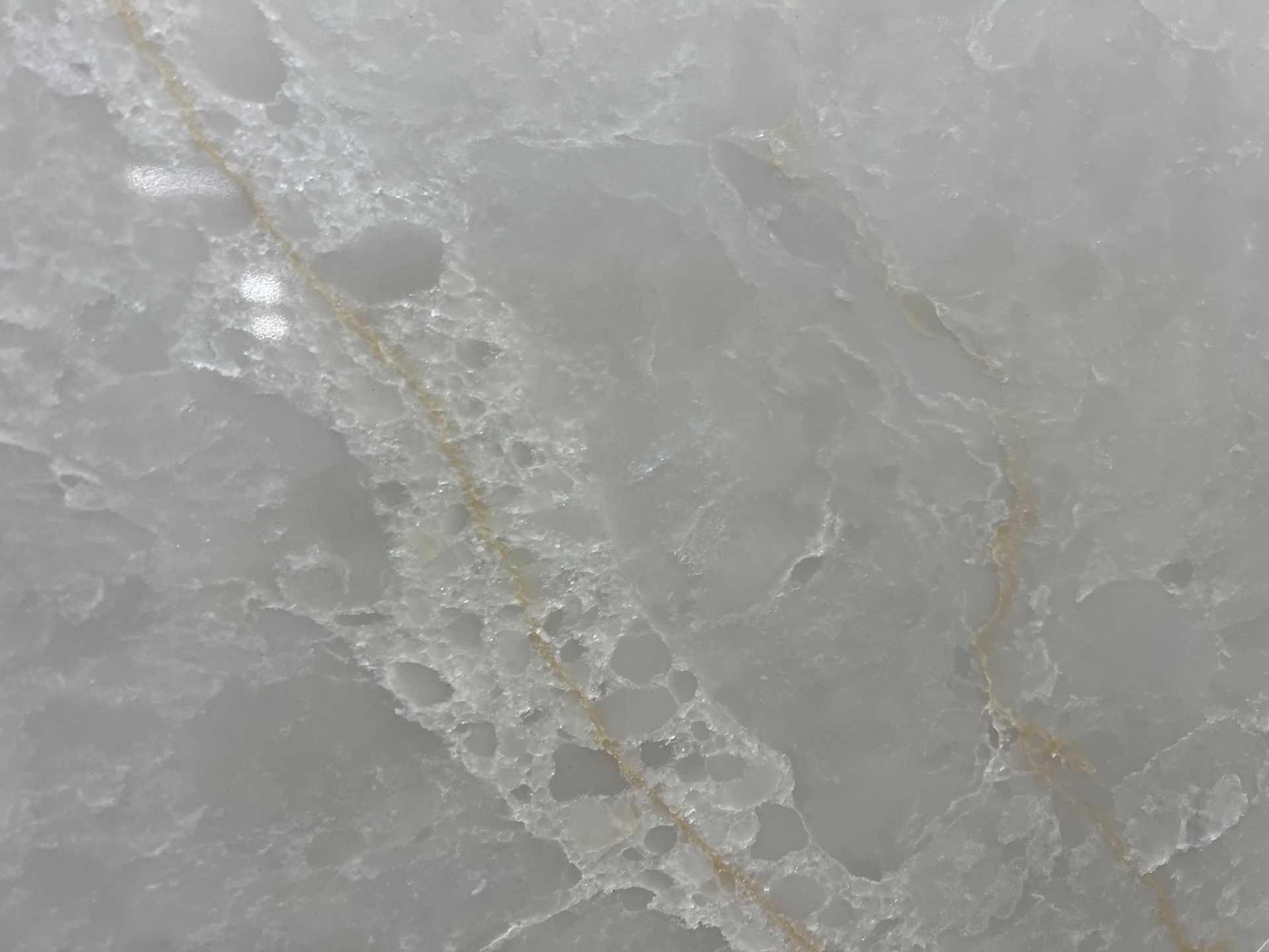 Close-up of pale gray, textured stone with white veining and faint tan streaks