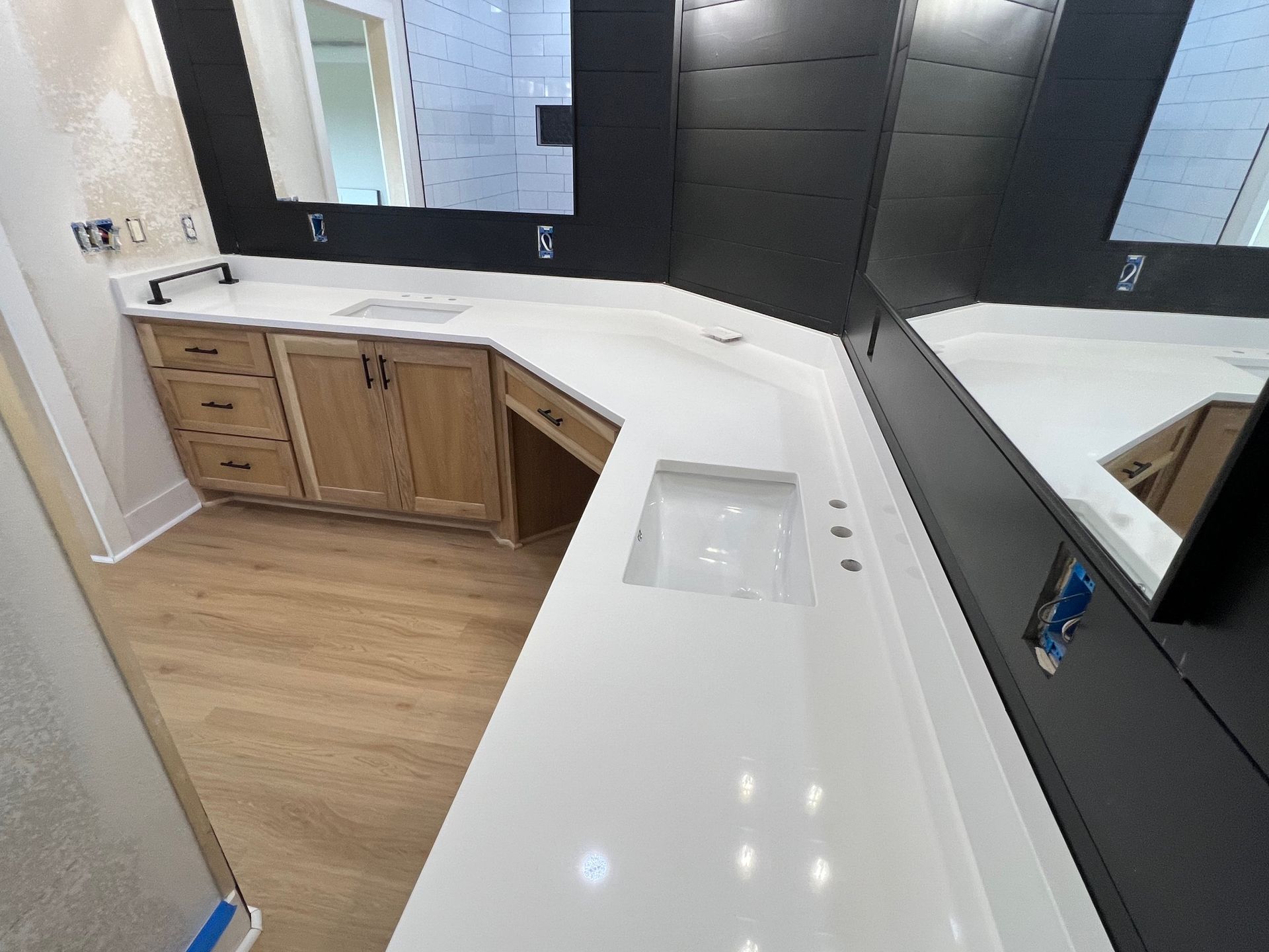 Modern bathroom with double vanity, black cabinetry, white countertops, and large mirror