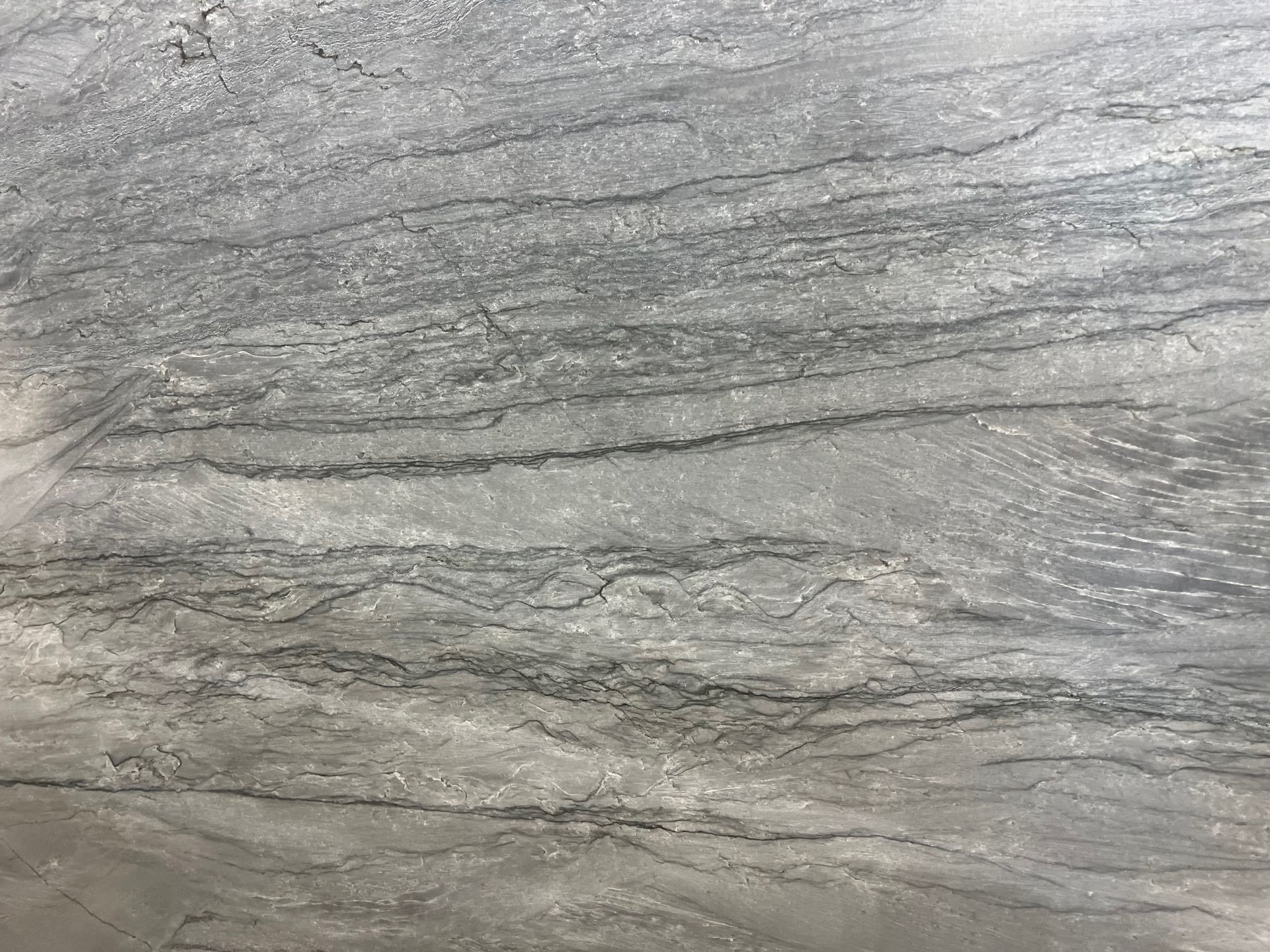 Gray textured rock surface with layered striations and subtle diagonal lines