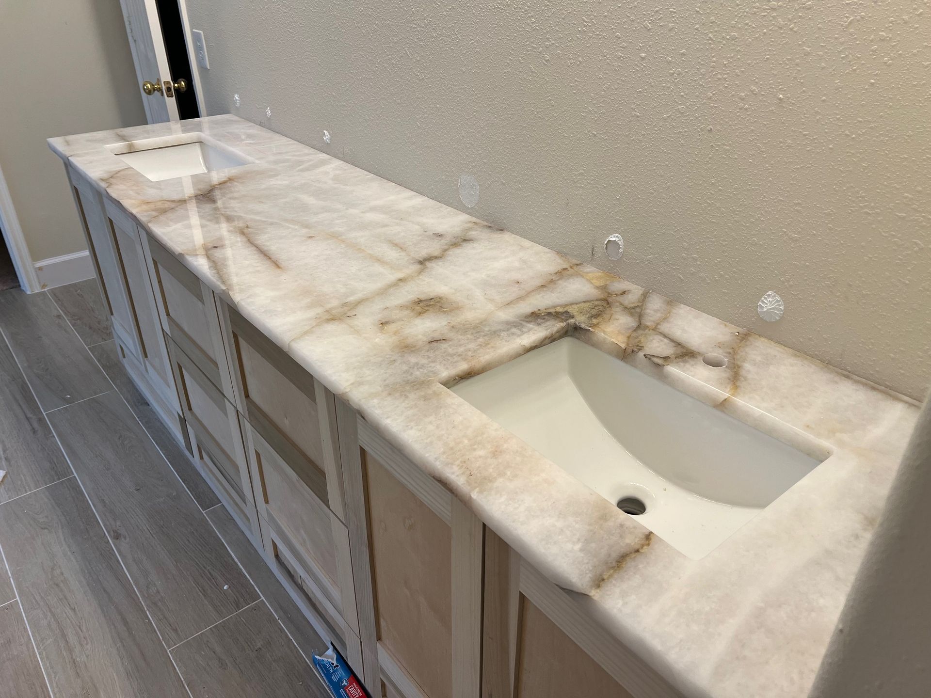 Long marble countertop with two sinks and cabinets in a modern bathroom.