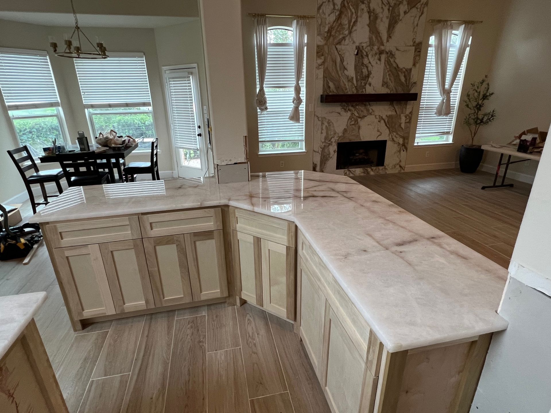Modern kitchen with light wood cabinets, marble island, and dining area overlooking water