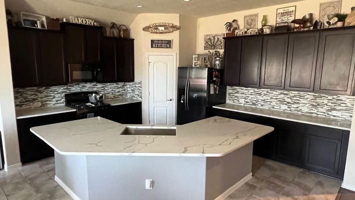 Modern kitchen with dark cabinets, white island, and black-and-white tile backsplash