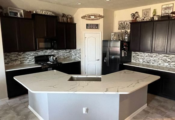 Modern kitchen with dark cabinets, white island, and stainless steel appliances