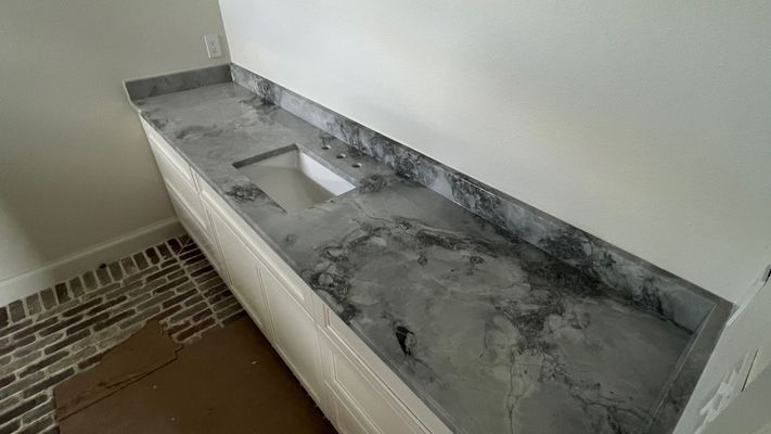Bathroom vanity with gray marble countertop and built-in sink against a white wall
