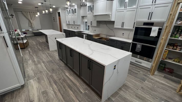 Bright modern kitchen with white cabinets, gray island, and wood-look flooring