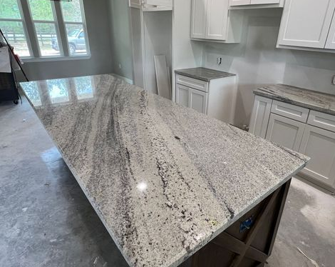 Kitchen with large speckled granite island countertop and white cabinets