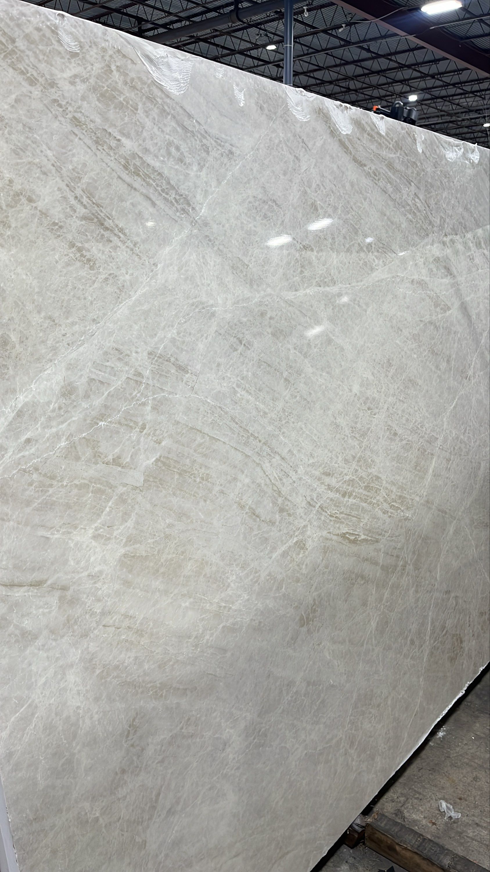 Large light-gray marble slab standing upright in a warehouse or stone showroom.