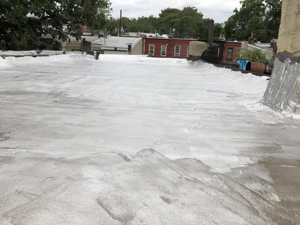 Rooftop with a white coated surface overlooking trees and low brick buildings