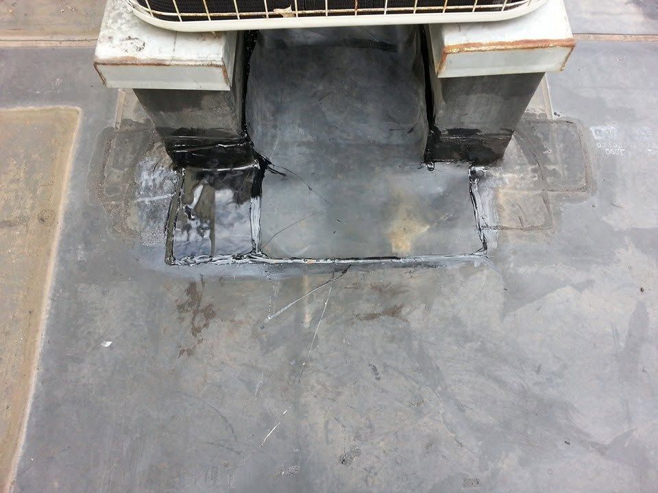 Damaged floor drain with a cracked concrete patch and dark stain around the opening