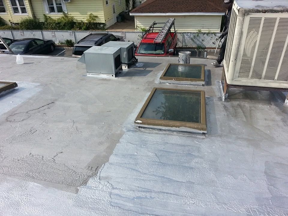 Rooftop with skylights, HVAC units, and a red service lift near a building wall