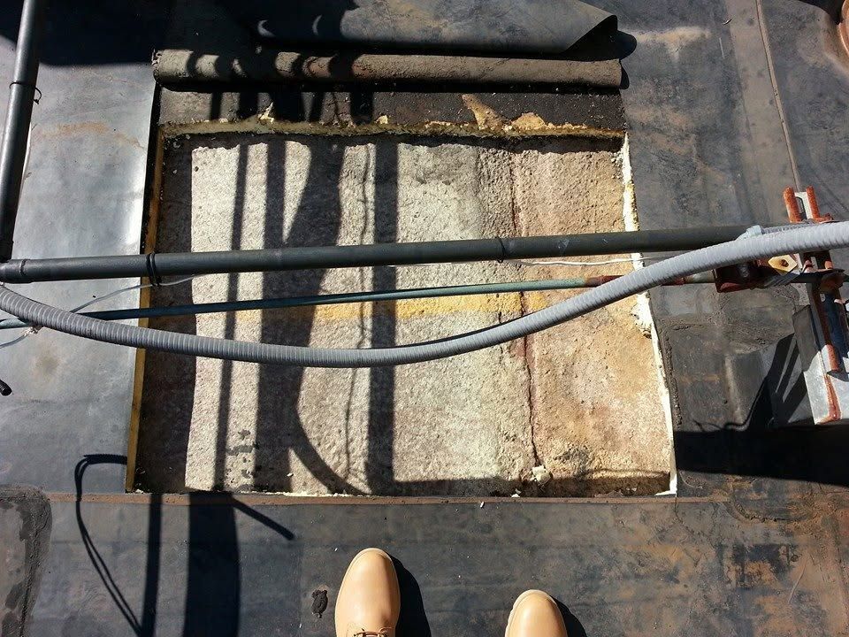 Rooftop HVAC unit with pipes, a weathered white panel, and a shoe visible at the bottom edge