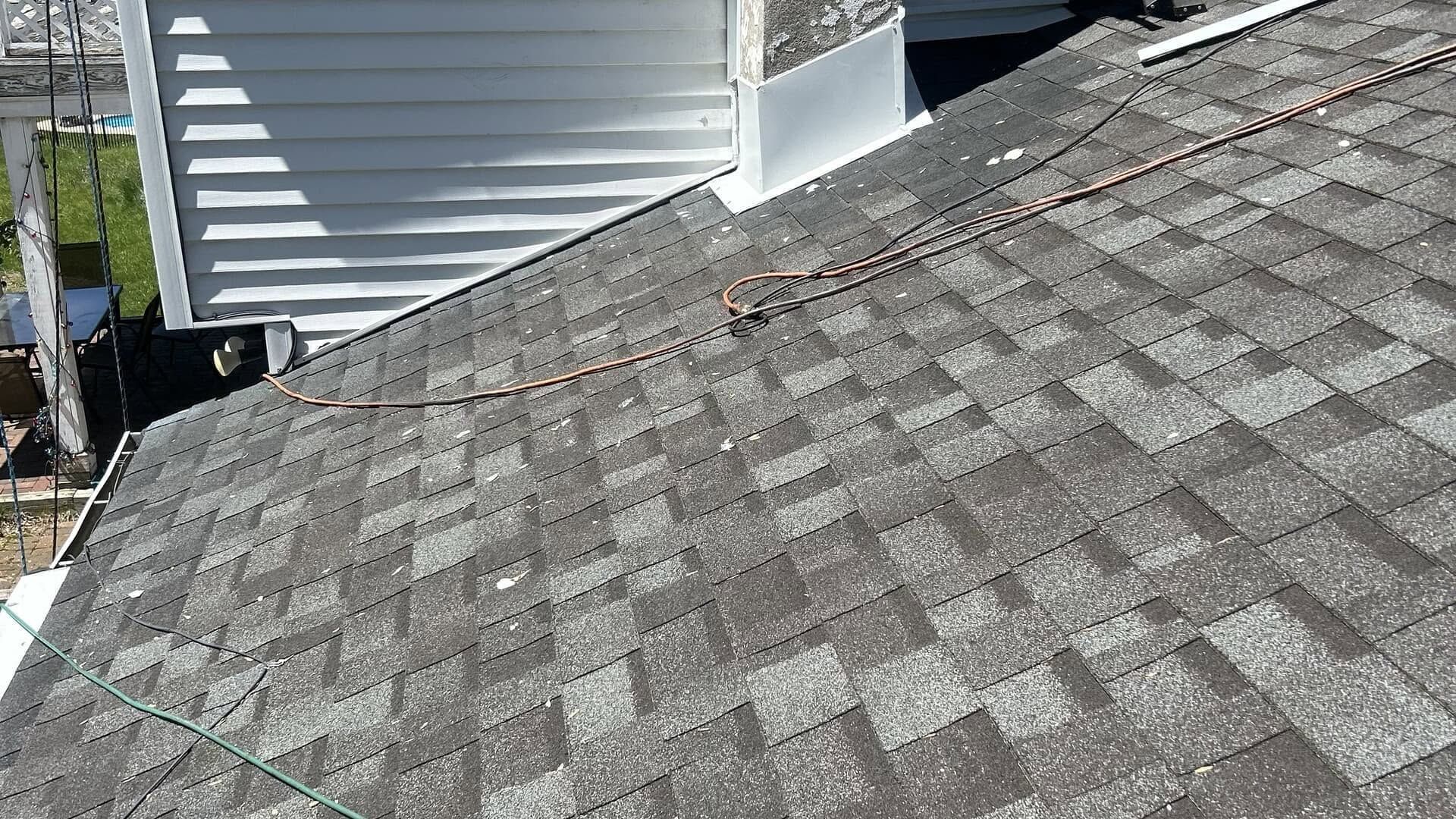 Gray shingled roof beside white vinyl siding on a house