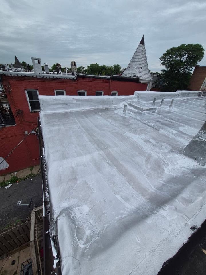 White tarp-covered roof beside red buildings under a cloudy sky, with a pointed tower in the background