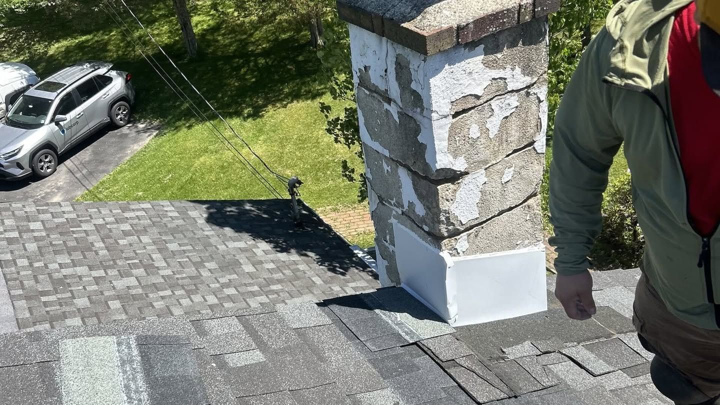 Stone chimney on a sloped roof beside a person in a green jacket, with a parked car below.