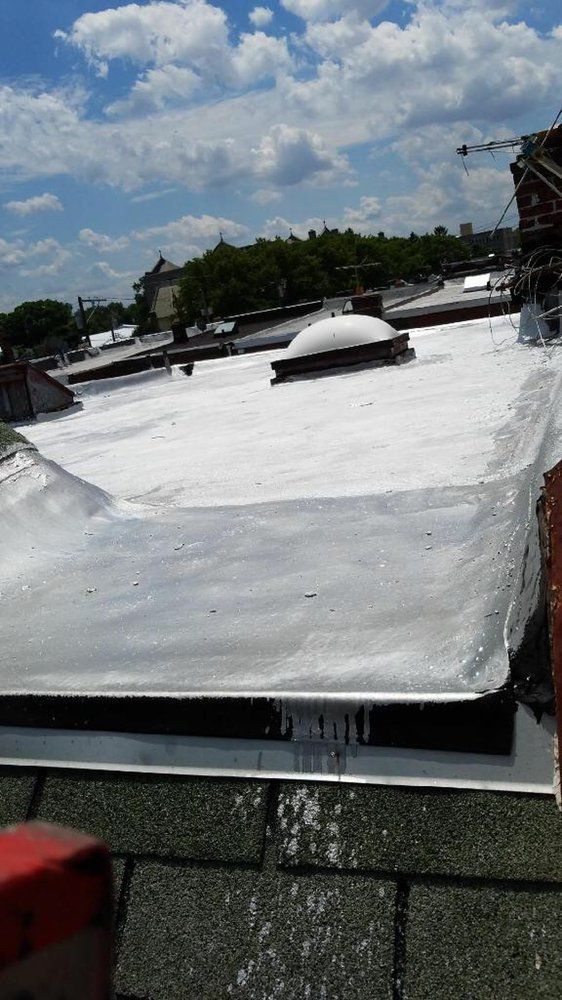 White rooftop under a cloudy blue sky, with vents and distant trees.