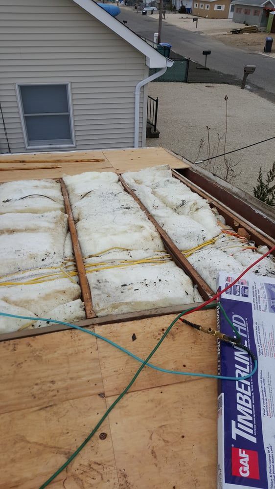 Rooftop underlayment and roof decking with straps, near a house and street view.