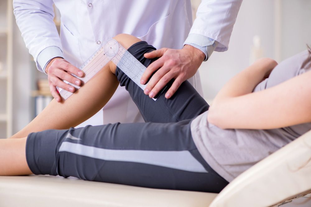 A Doctor Is Examining A Patient 's Leg In A Hospital — Physiocare In Maroochydore, QLD