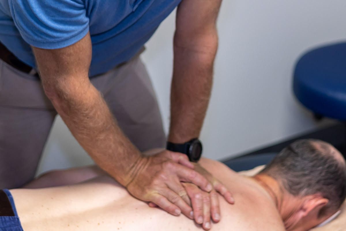 A Man Is Laying On A Table Getting A Massage From A Doctor — Physiocare In Buderim, QLD