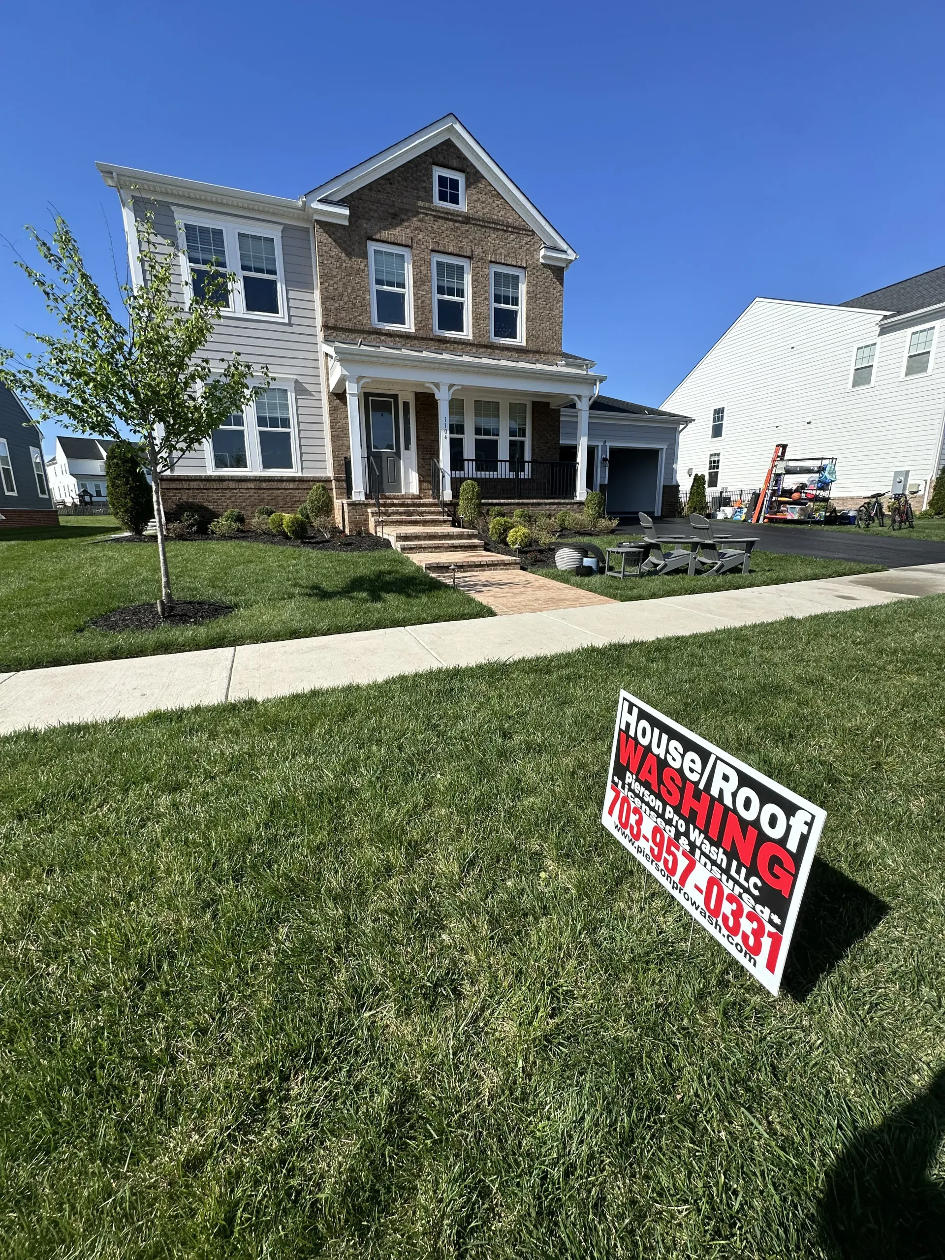 New house with a for-sale sign on a sunny suburban lawn