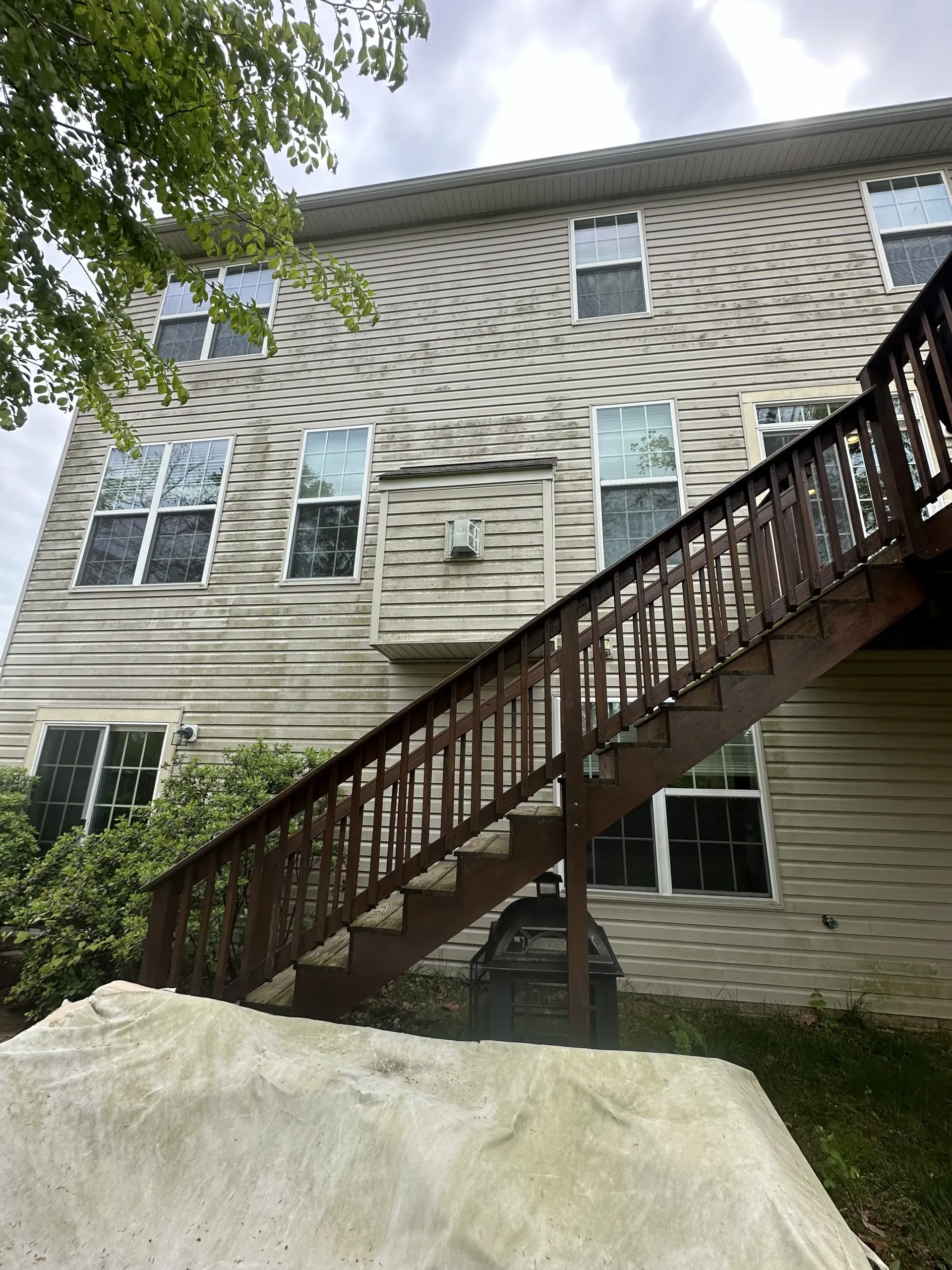 Backyard view of a house with an exterior staircase and a large mound of dirt in front