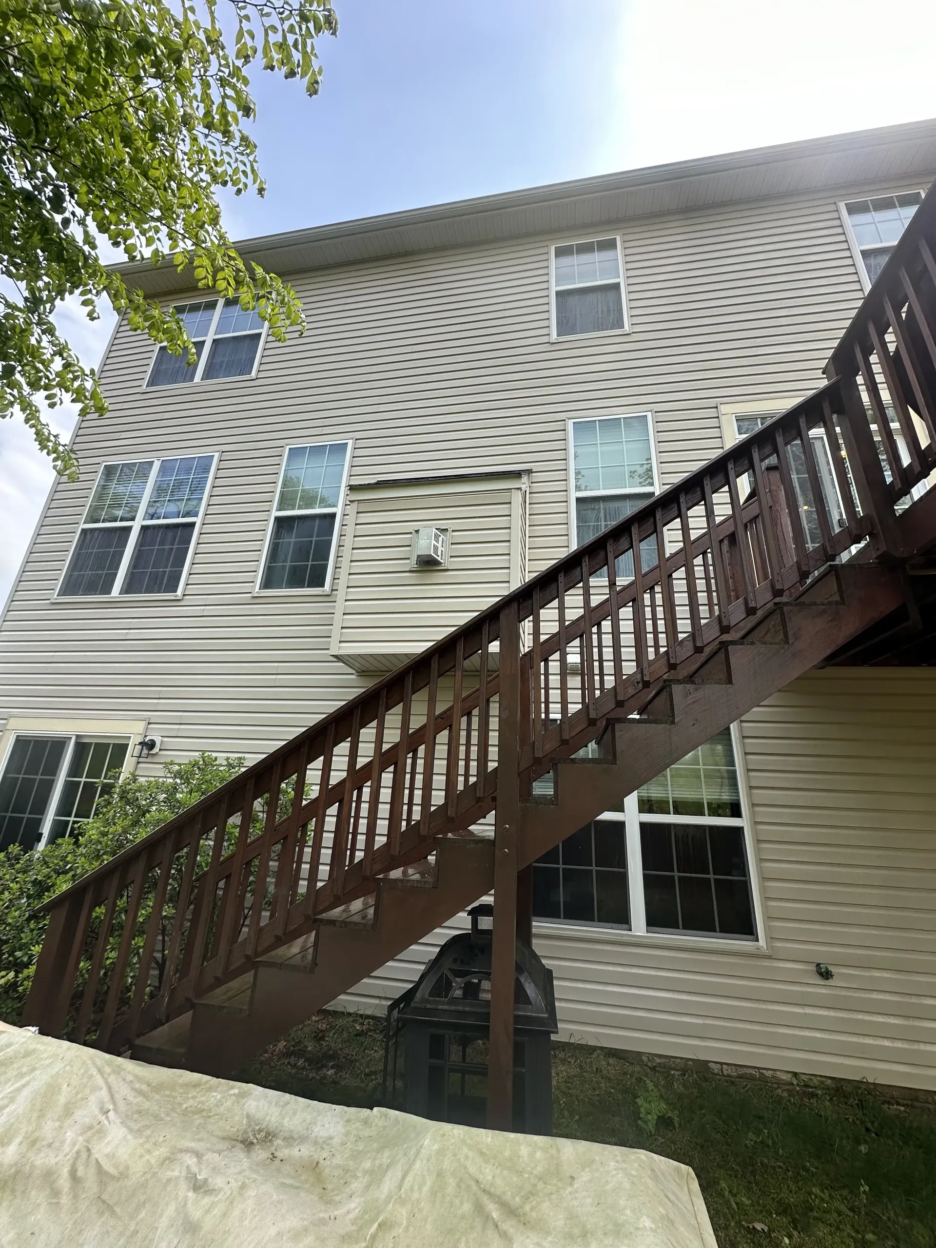 Apartment building with a brown exterior staircase leading to upper floors and windows.