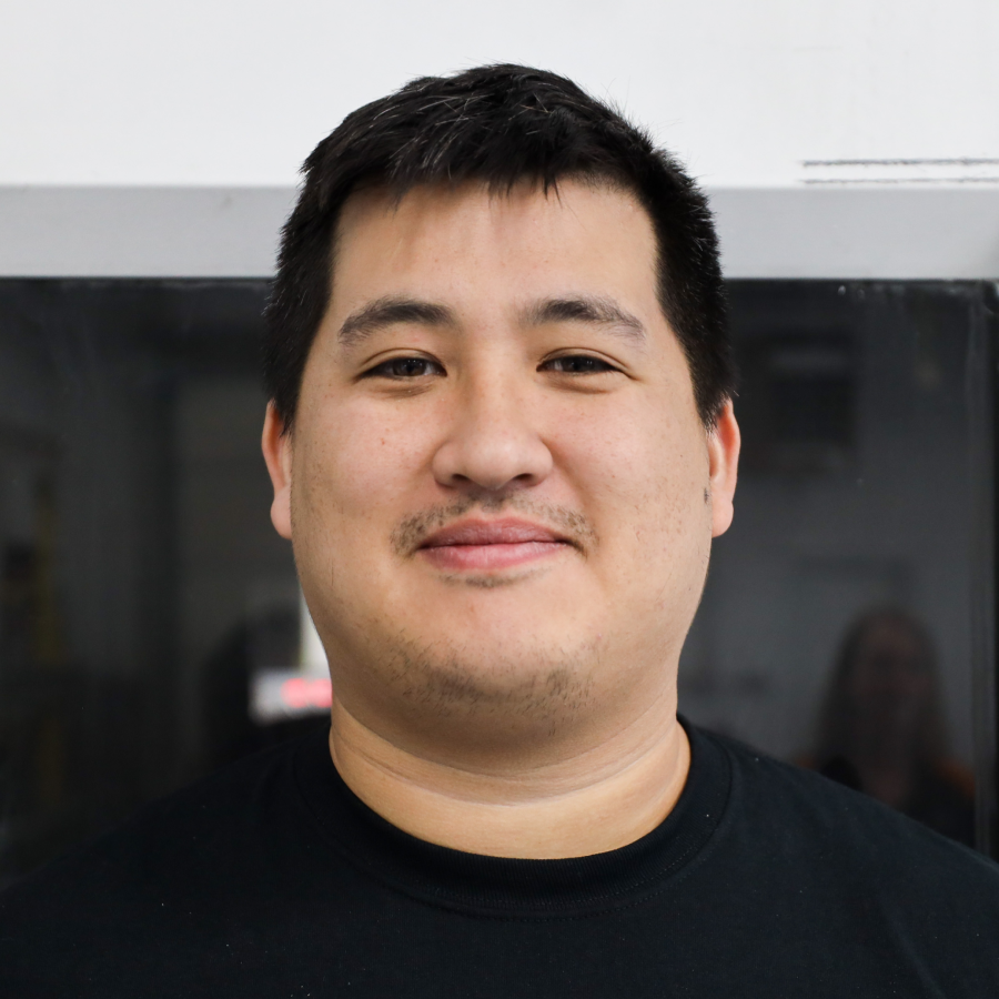 A man with a mustache is wearing a black shirt and smiling