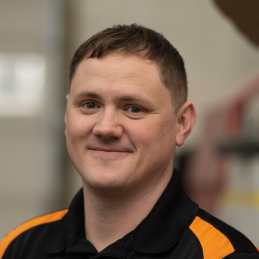 A man wearing a black and orange shirt is smiling for the camera