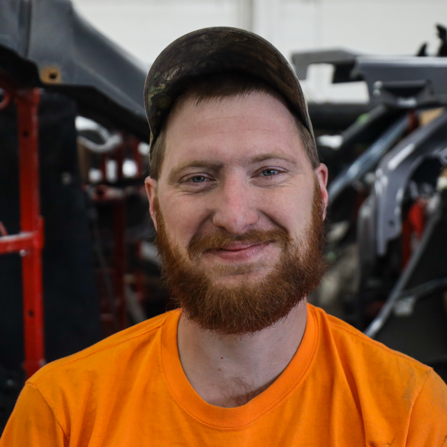 A man with a beard wearing an orange shirt and hat