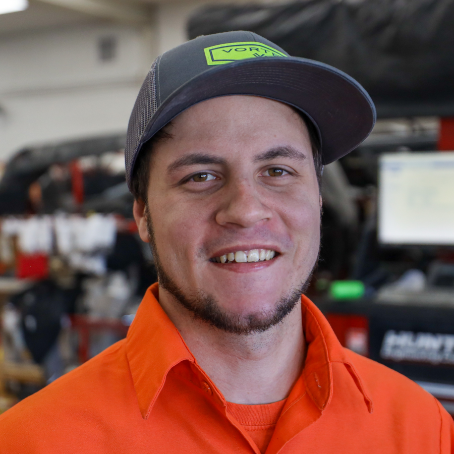 A man wearing an orange shirt and a hat is smiling