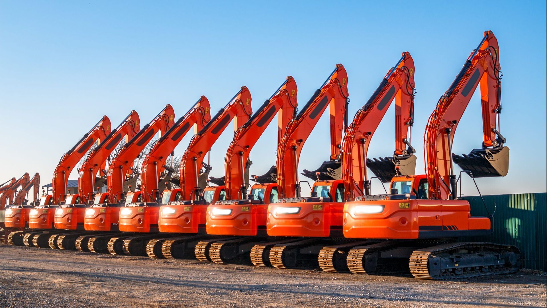 Une rangée de pelleteuses orange garées à l'extérieur.