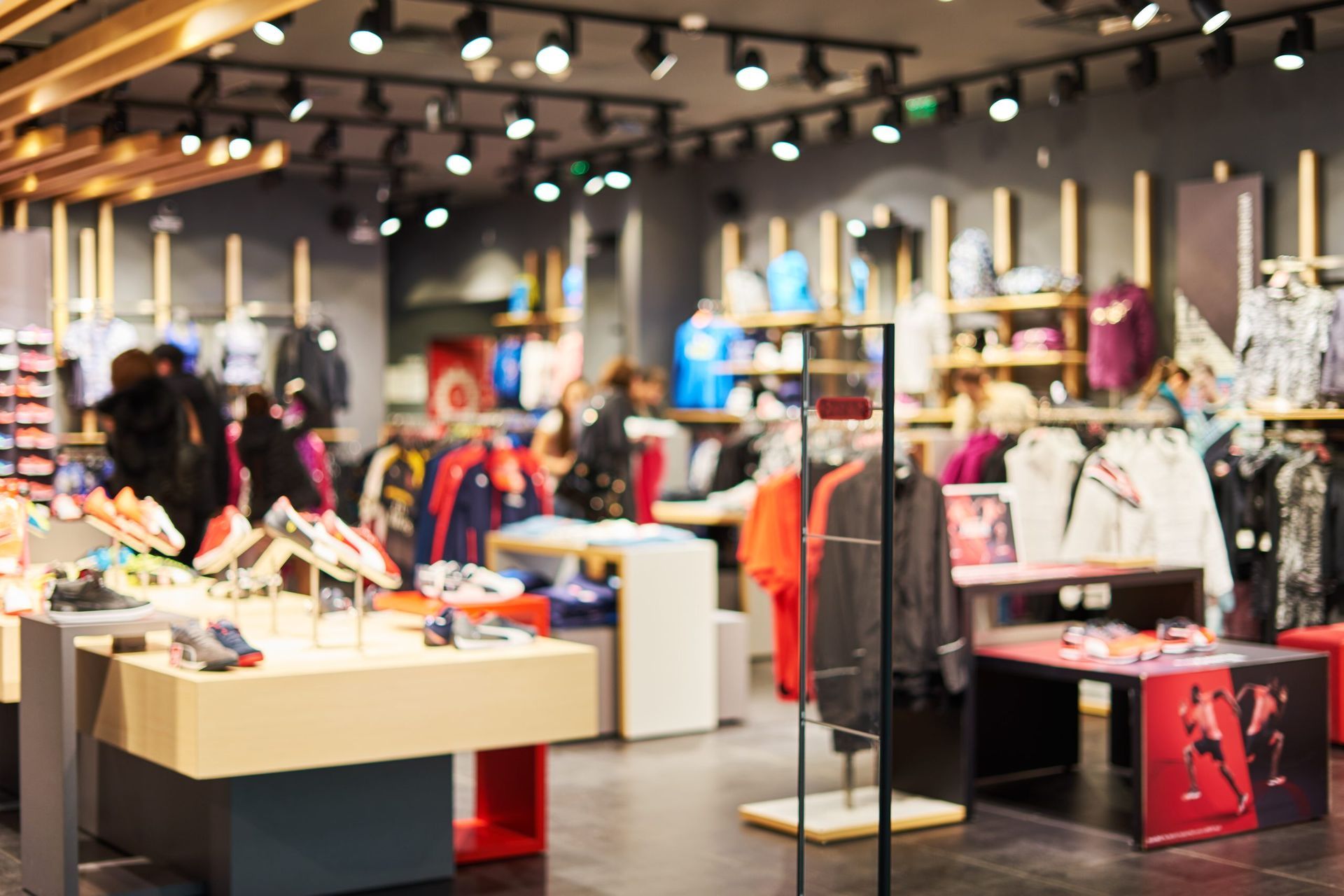Intérieur d'un magasin de vêtements et de chaussures avec tables d'exposition et portants de vêtements.