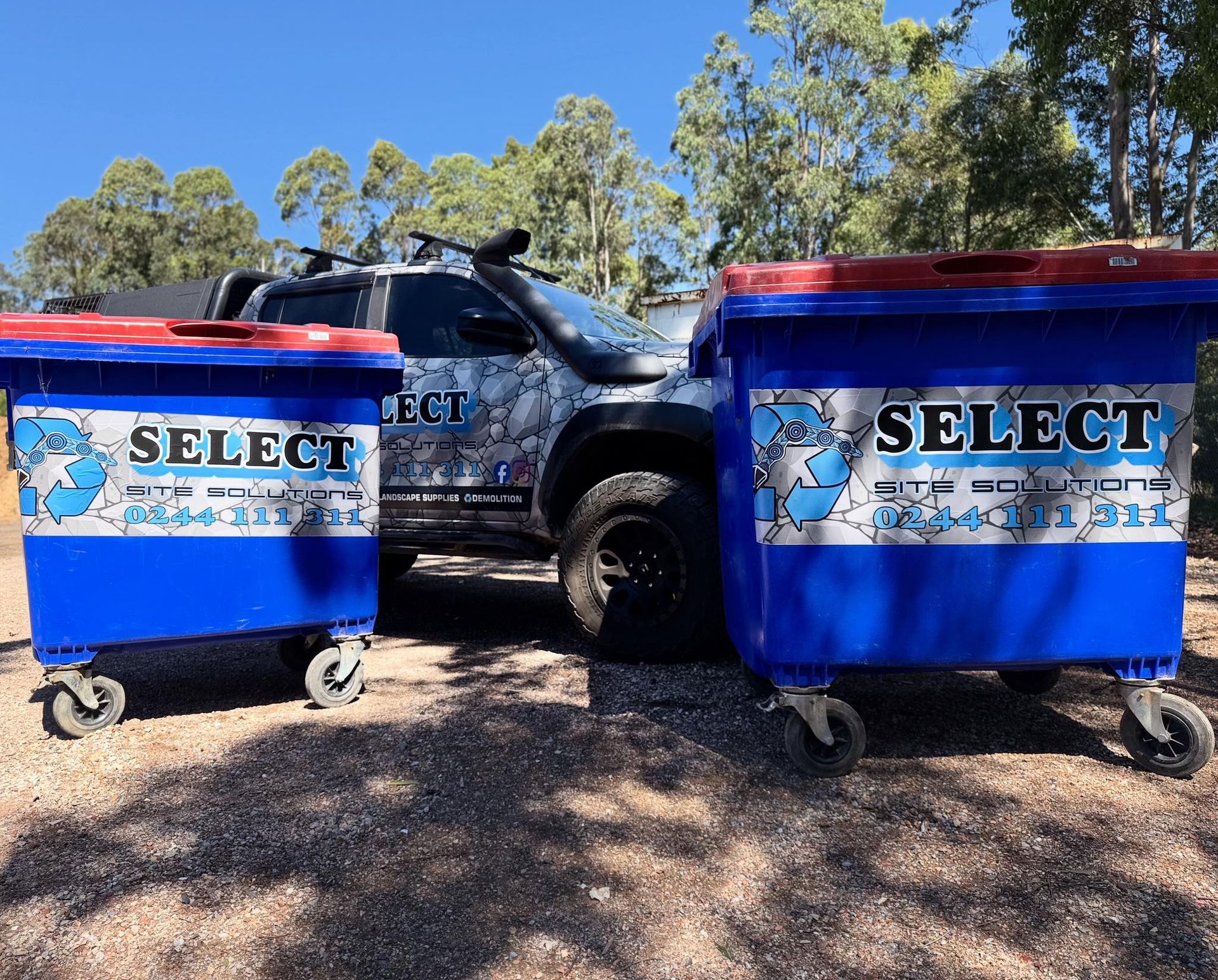 Two blue recycling bins with red lids and company logo, beside a camouflage pickup truck, outdoors. — Select Site Solutions in Lake Conjola, NSW
