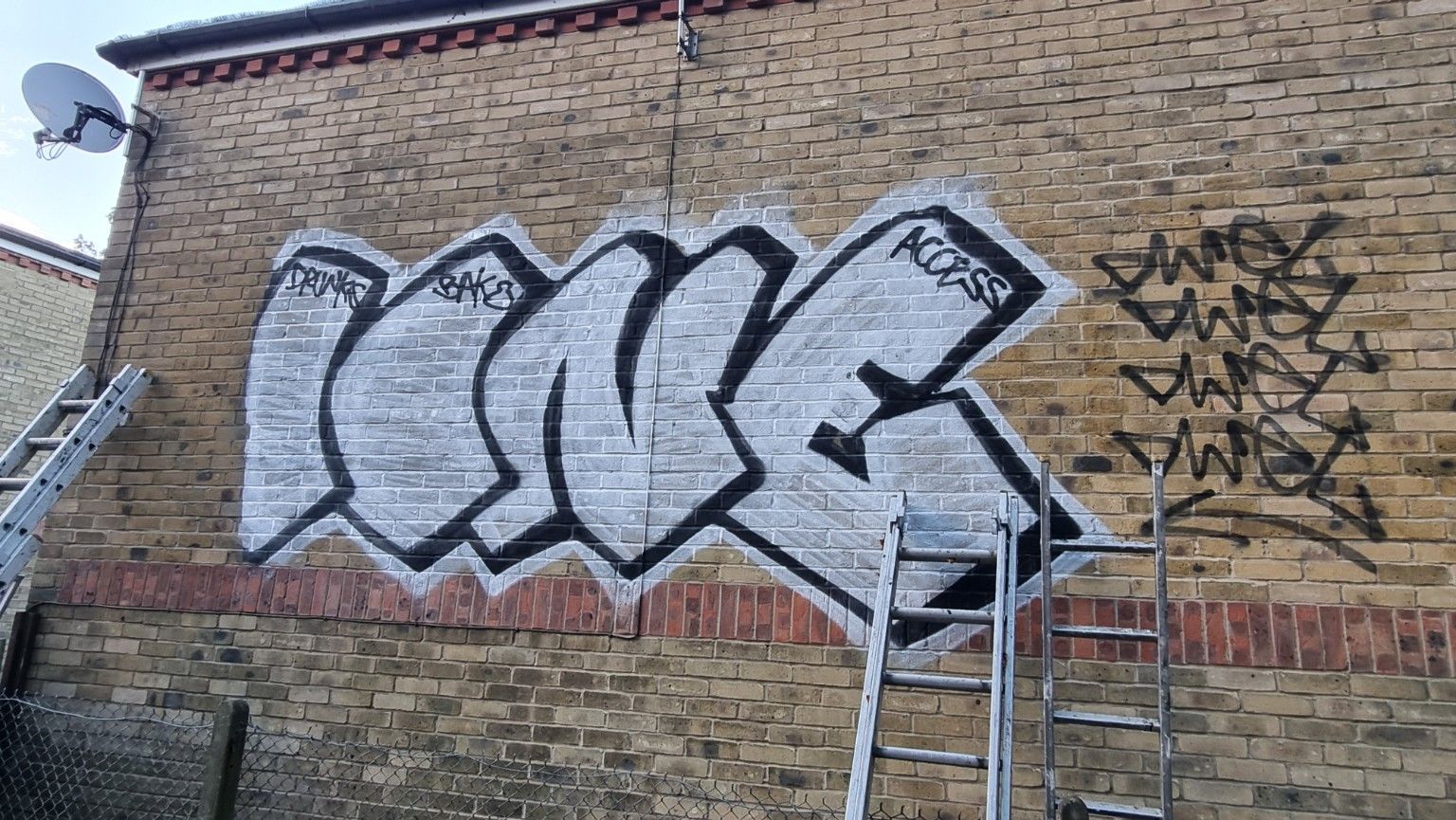 Graffiti on brickwork back of house partial removal