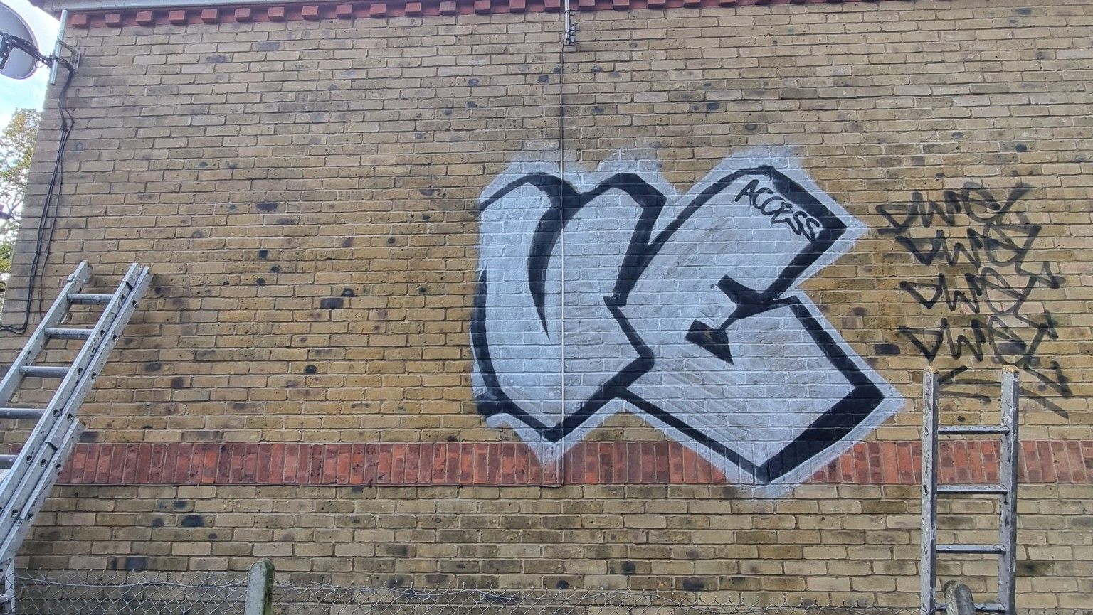 Graffiti on brickwork back of house partial removal 2