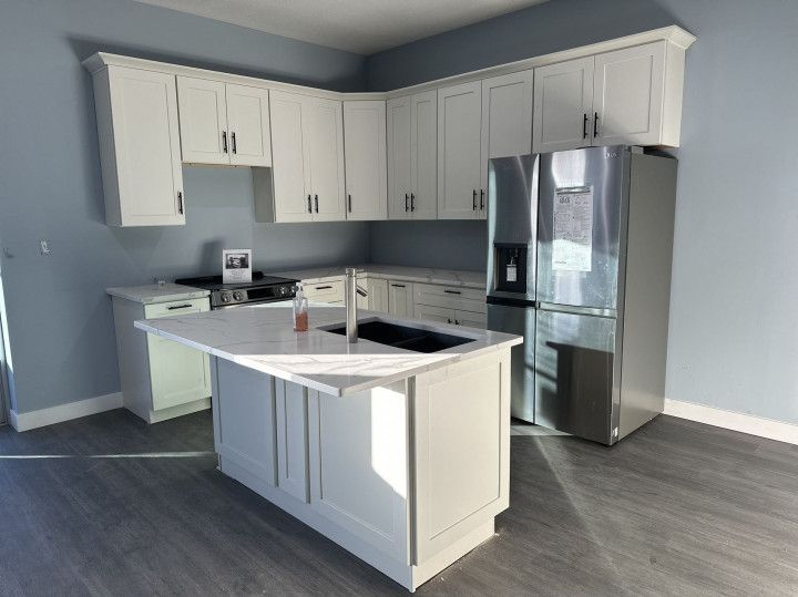 White kitchen cabinets with stainless steel appliances and an island on gray flooring.